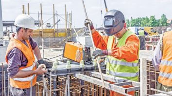 Zrenjanin, Vojvodina, Serbia - May 29, 2015: Industrial shot of construction workers who are welding metal frame, cage of armature inside of demountable wooden mold for concreting pillar base.