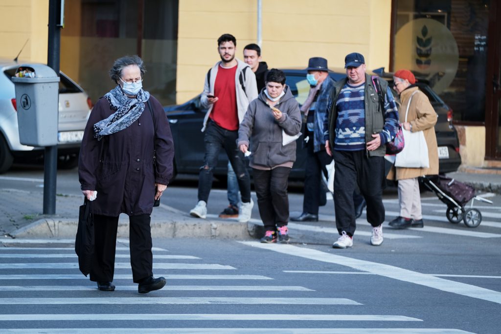 Femeie traversează o stradă purtând o mască