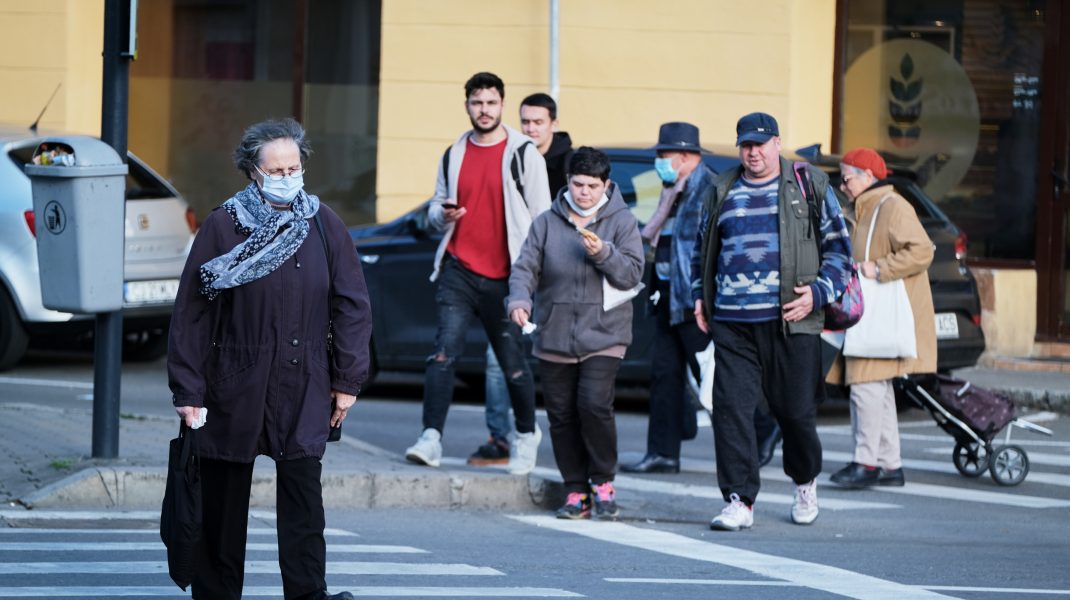 Femeie traversează o stradă purtând o mască