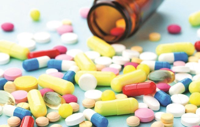 Colorful drug pills on blue background, pharmaceutical concept