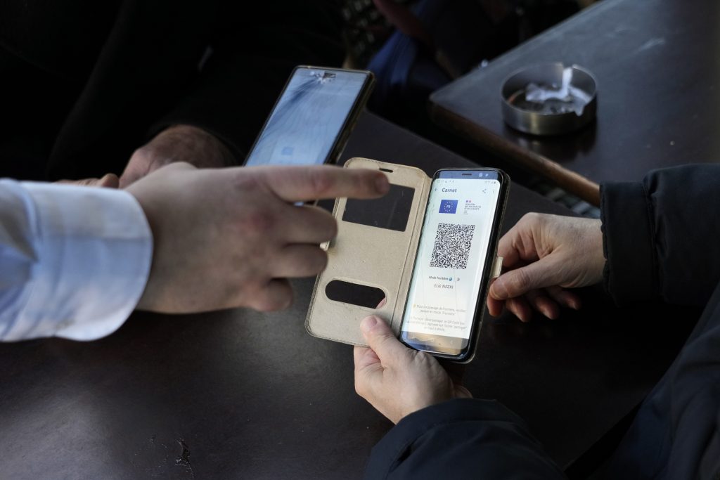 A waiter checks clients' vaccine pass in a restaurant, in Paris, Monday, Jan. 24, 2022. Unvaccinated people are no longer allowed in France's restaurants, bars, tourist sites and sports venues. A new law came into effect Monday requiring a "vaccine pass" that is central to the government's anti-virus strategy. (AP Photo/Thibault Camus)