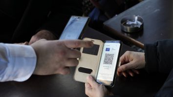 A waiter checks clients' vaccine pass in a restaurant, in Paris, Monday, Jan. 24, 2022. Unvaccinated people are no longer allowed in France's restaurants, bars, tourist sites and sports venues. A new law came into effect Monday requiring a "vaccine pass" that is central to the government's anti-virus strategy. (AP Photo/Thibault Camus)