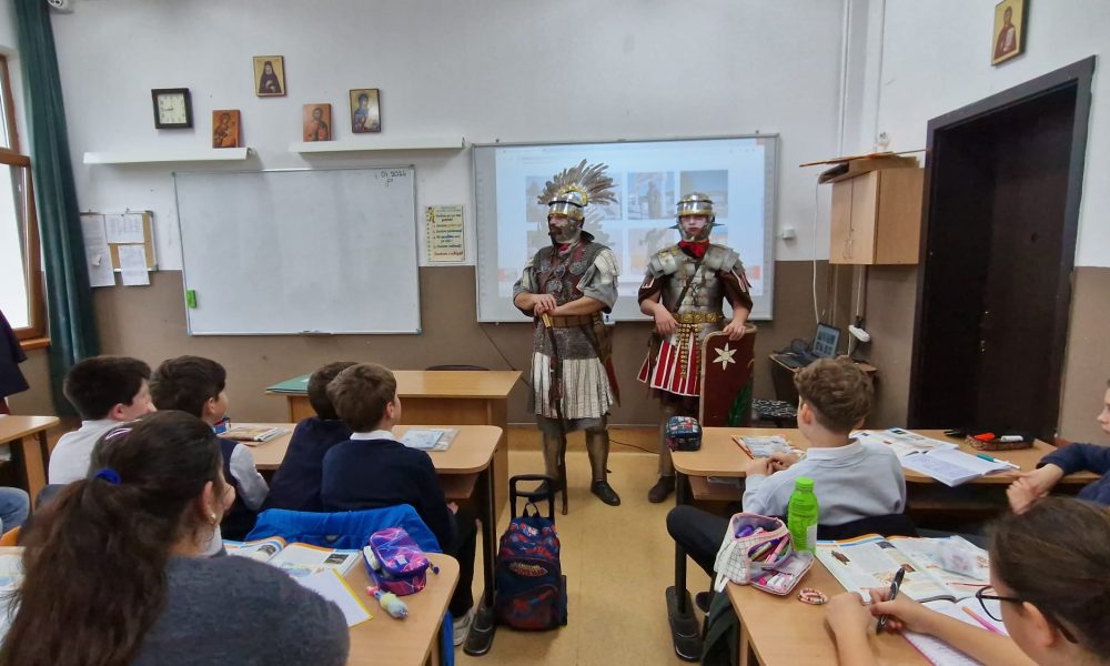 Elevii din Alba Iulia au participat la o lecție inedită de istorie despre Imperiul Roman. 2 membri ai Gărzii Romane din Apulum au fost invitați la oră