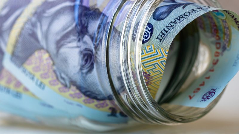 Composition with saving money romanian LEI banknotes in a glass jar. Concept of investing and keeping money, close up isolated.