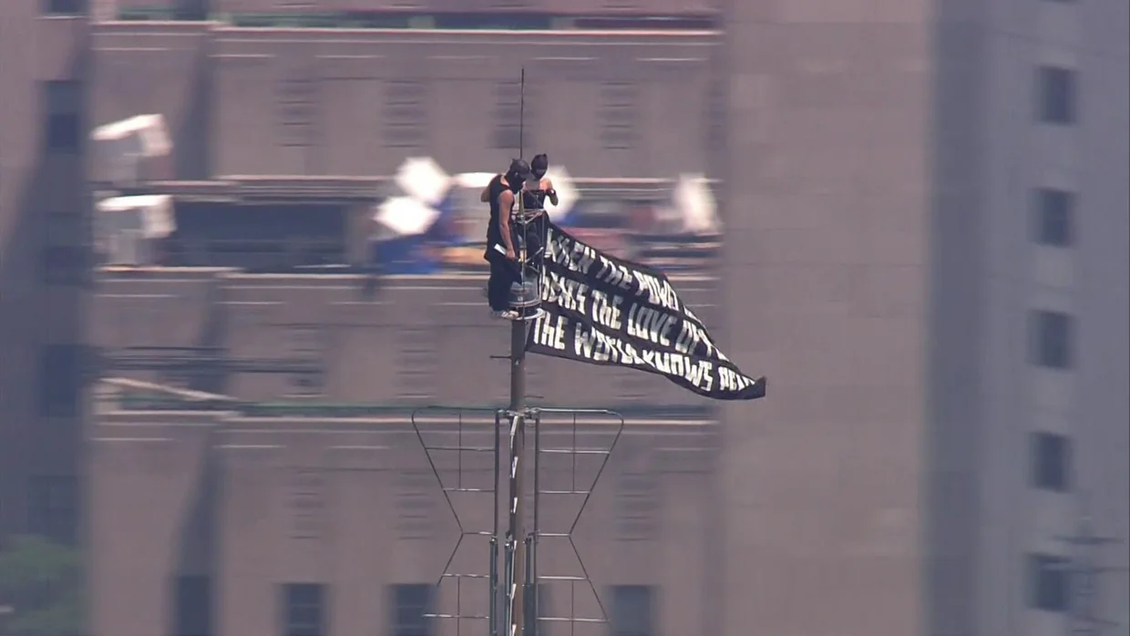 Imagini incredibile din New York: Două persoane mascate au urcat în vârful Empire State Building, cu un banner pentru pace: „Când puterea iubirii va învinge iubirea pentru putere, va fi pace în lume”