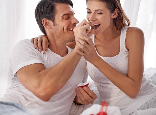 Shot of an affectionate young husband feeding his wife chocolate