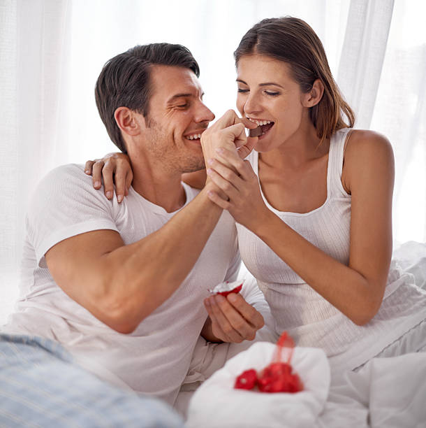 Shot of an affectionate young husband feeding his wife chocolate