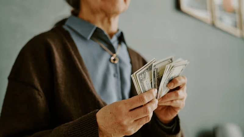 Senior woman holding counting money dollar bills 1200x628 facebook
