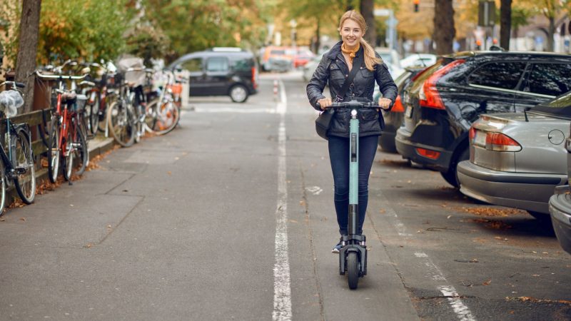 Young happy woman riding an electric scooter in the city